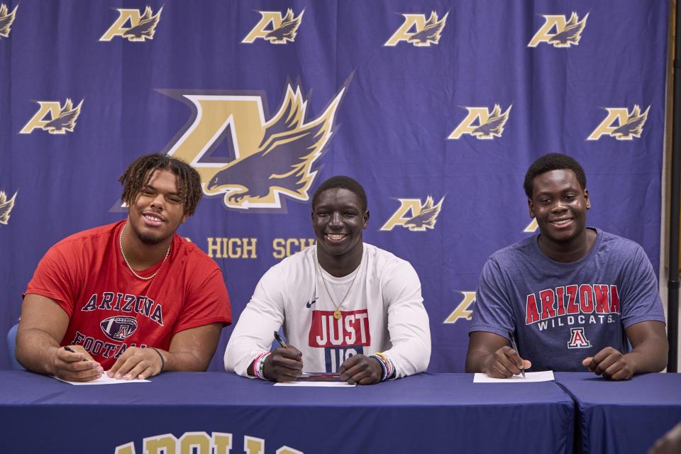 (Left to right) Apollo Hawks offensive lineman Michael Watkins, running back Adam Mohammed and offensive lineman Matthew Lado sign their commitment papers to the University of Arizona at Apollo High School in Glendale on Dec. 20, 2023.