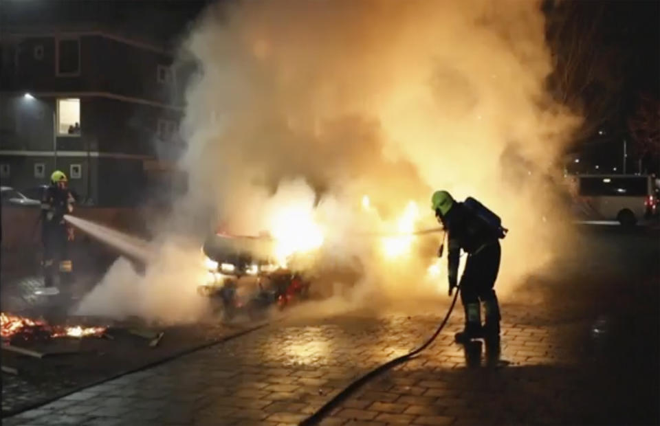 In this grab taken from video on Monday, Jan, 25, 2021, firefighters extinguish a vehicle set on fire by rioters, in Haarlem, Netherlands. Groups of youths have confronted police in several Dutch cities defying the country’s coronavirus curfew and throwing fireworks. Police in the port city of Rotterdam used a water cannon and tear gas in an attempt to disperse a crowd of rioters Monday night. (Mizzle Media via AP)