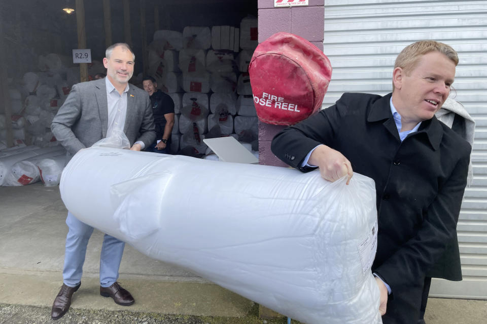 New Zealand's Prime Minister Chris Hipkins, right, helps carry some home insulation during a campaign stop in New Plymouth on Monday, Sept. 25, 2023. With less than three weeks to go until a general election, opinion polls have put Hipkins and his Labour Party significantly behind the National Party, led by former businessman Christopher Luxon. (AP Photo/Nick Perry)