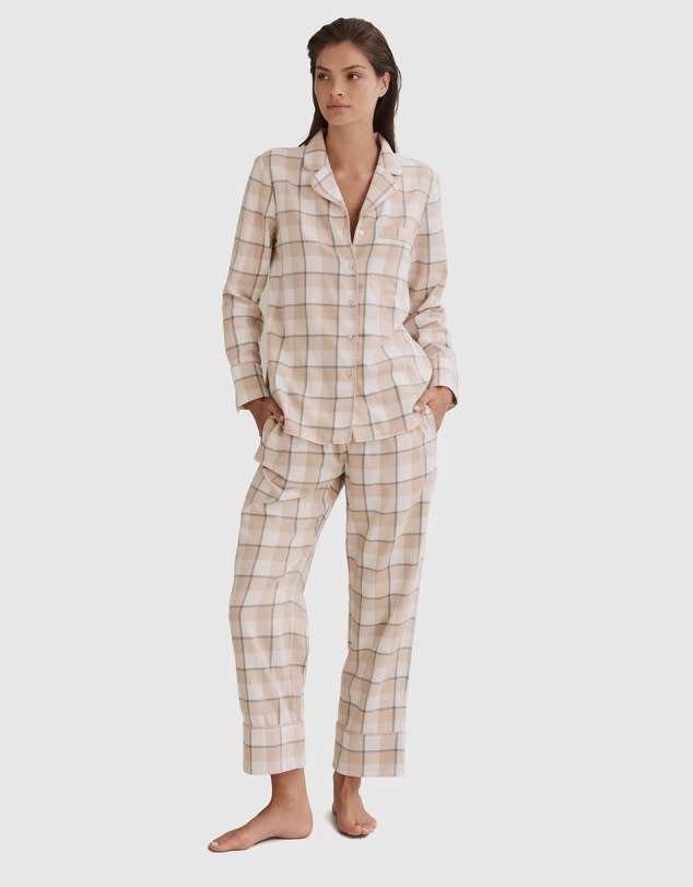 A brunette woman standing in comfy two tone beige sleepwear 