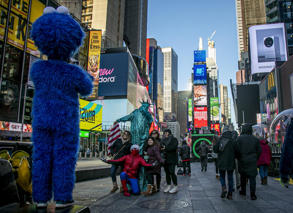 In this Thursday, Dec. 19, 2019 photo, people snap pictures with familiar costumed characters, who solicit money to perform for the photos in Times Square in New York. Complaints about the sometimes aggressive behavior of the performers prompted the city in 2016 to passed a law relegating the Times Square characters to 8-by-50 foot “activity zones" where they might annoy fewer people. (AP Photo/Bebeto Matthews)
