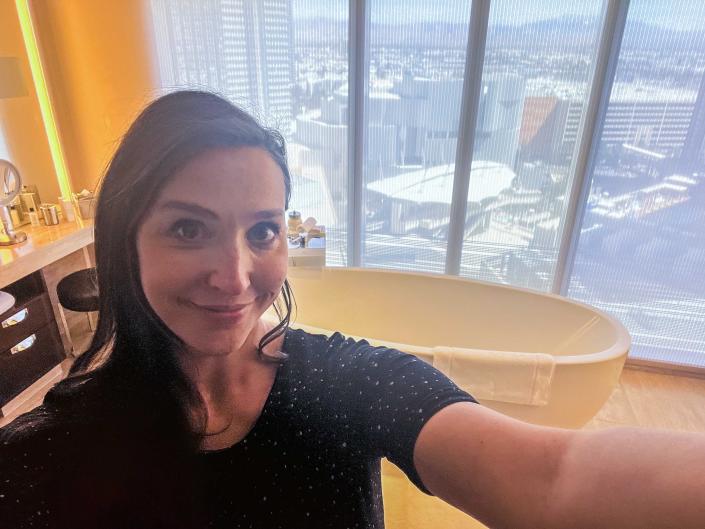 A woman takes a selfie in front of a fancy tub.