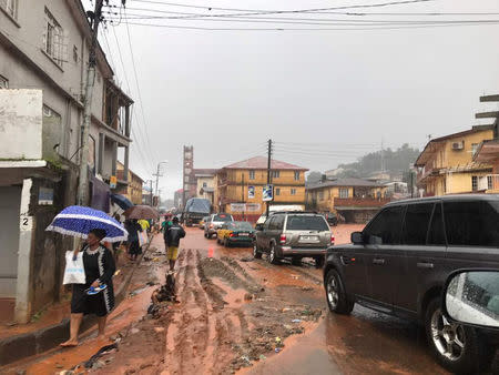 People walk under rain along a street in Freetown, Sierra Leone August 14, 2017 in this picture obtained from social media. Instagram/dawncharris via REUTERS