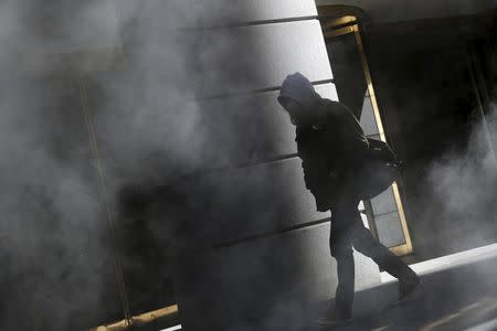 A man walks through the Financial District in New York February 14, 2016. REUTERS/Andrew Kelly