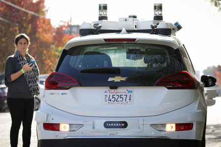 A woman uses her phone before getting in a self-driving Bolt EV car during a media event by Cruise, GM’s autonomous car unit, in San Francisco, California, U.S. November 28, 2017. REUTERS/Elijah Nouvelage