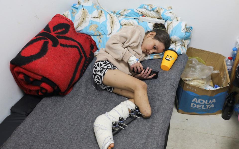 Palestinian girl Eman Al-Kholi, whose limb was amputated after being wounded in an Israeli strike that killed her parents, lies on a bed as she receives treatment at the European Hospital, in Rafah