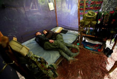 A couple from the 51st Front of the Revolutionary Armed Forces of Colombia (FARC) rest inside a tent at a camp in Cordillera Oriental, Colombia, August 16, 2016. Picture taken August 16, 2016. REUTERS/John Vizcaino
