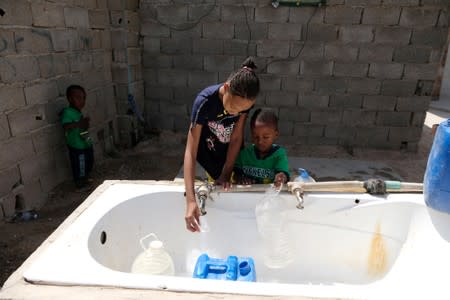 Libyan children displaced from the town of Tawergha fill containers with water at a displaced camp in Benghazi