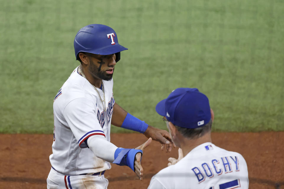 Texas Rangers' Ezequiel Duran, left, is greeted by manager Bruce Bochy, right, after scoring a run against the Arizona Diamondbacks during the fifth inning of a baseball game against the Texas Rangers, Tuesday, May 2, 2023, in Arlington, Texas. (AP Photo/Michael Ainsworth)