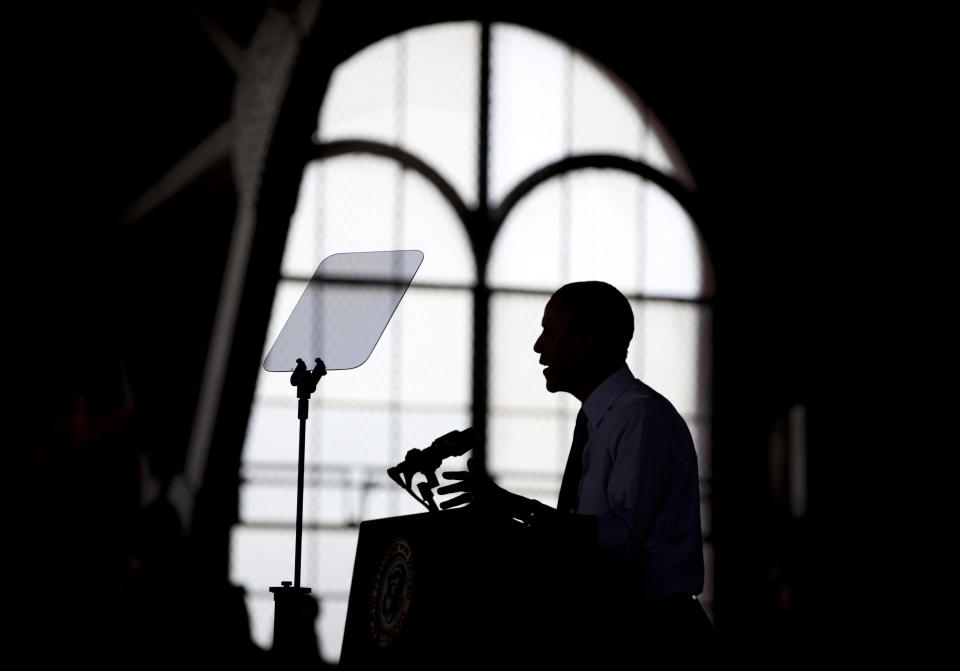 In this April 2, 2014, photo, President Barack Obama is silhouetted as he speaks at the University of Michigan, in Ann Arbor, Mich., about his proposal to raise the national minimum wage. The roller coaster of health care enrollment behind him, Obama is using a lull between foreign travel to refocus on his economic agenda, using executive actions to push for greater gender pay equality and to promote better technical skills for U.S. students.(AP Photo/Carolyn Kaster)