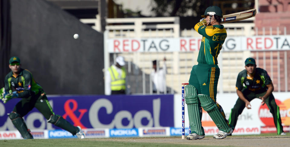 South African batsman Quinton de Kock (C) plays a shot as Pakistani wicket keeper Umar Akmal (L) looks on during the fifth and final day-night international at Sharjah Cricket Stadium in Sharjah on November 11, 2013. South Africa lead the five-match series 3-1. AFP PHOTO/Asif HASSAN