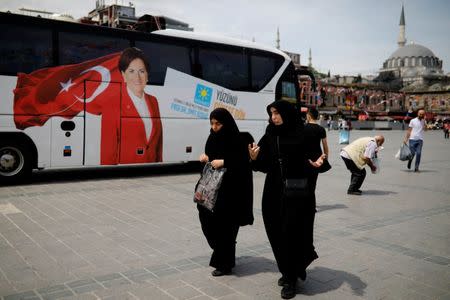 Two women make their way next to a bus with a picture of Iyi (Good) Party leader Meral Aksener in Eminonu district in Istanbul, Turkey, June 21, 2018. REUTERS/Alkis Konstantinidis