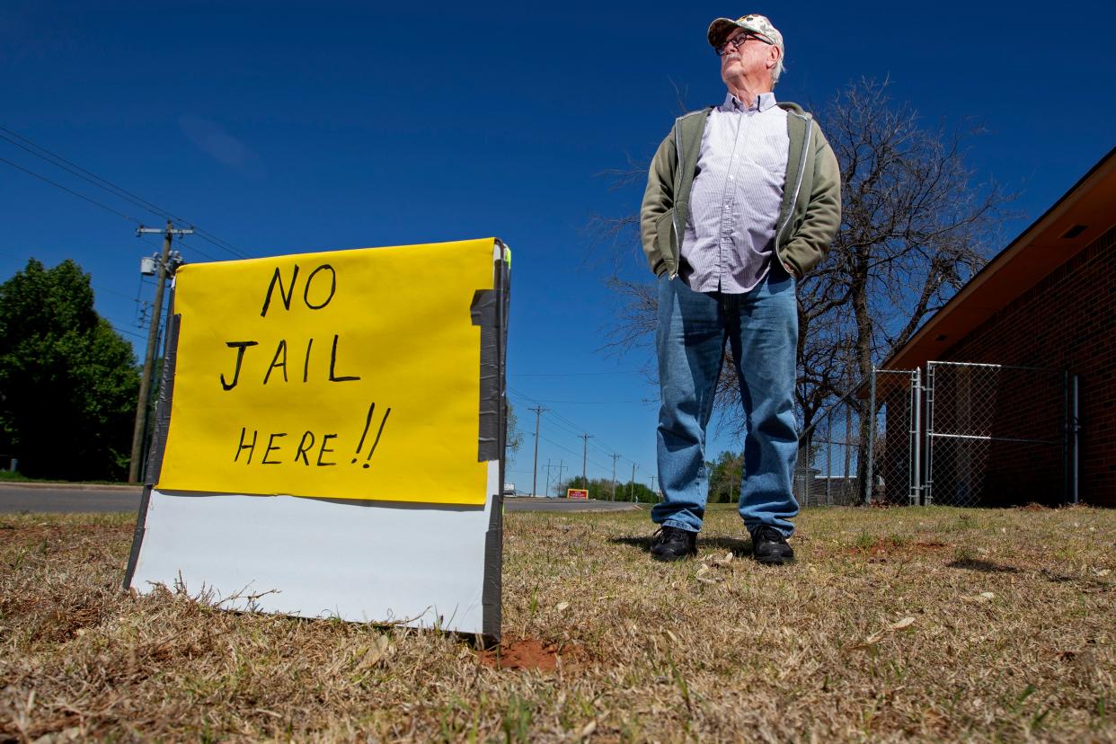 Robert Koon stands near a sign this month outside his Del City home. Koon is against the proposed new county jail location close to his Del City home.