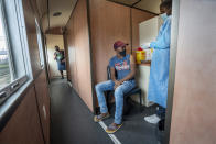 A person receives a COVID-19 vaccine on a train at the Swartkops railroad yard outside Gqeberha, South Africa, Thursday Sept. 23, 2021. South Africa has sent a train carrying COVID-19 vaccines into one of its poorest provinces to get doses to areas where healthcare facilities are stretched. The vaccine train, named Transvaco, will go on a three-month tour through the Eastern Cape province and stop at seven stations for two weeks at a time to vaccinate people. (AP Photo/Jerome Delay)