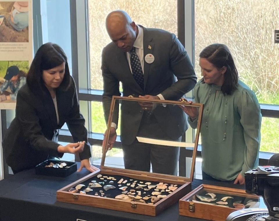 Dr. Julie Schablitsky, MDOT chief of cultural affairs shows, Gov. Wes Moore some of the artifacts unearthed during the dig. Sarah Janesko, director of MDOT archaeology lab, looks on.