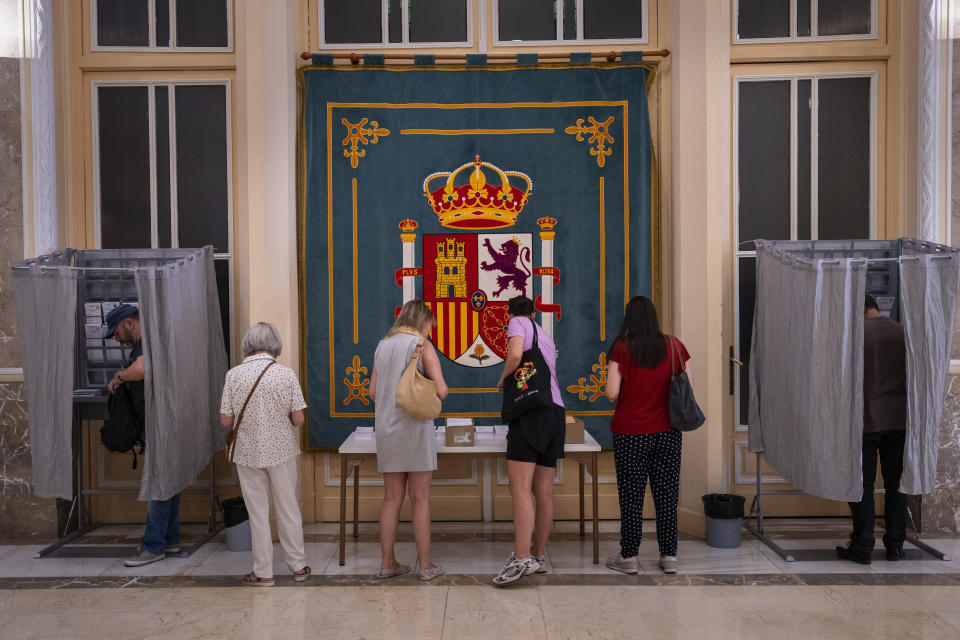 People pick their ballots before voting at a polling station for Spain's general election, in Madrid, Sunday, July 23, 2023. Sunday's election could make the country the latest European Union member to swing to the populist right, a shift that would represent a major upheaval after five years under a left-wing government. (AP Photo/Emilio Morenatti)
