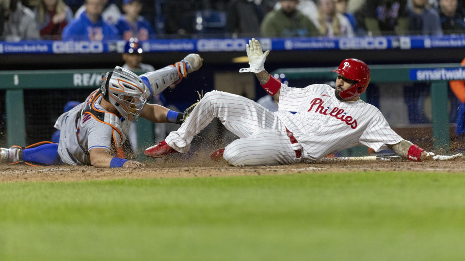 Philadelphia Phillies' Nick Castellanos, right, scores on an RBI double by Rhys Hoskins before New York Mets catcher James McCann (33) can make the tag during the eighth inning of a baseball game, Monday, April 11, 2022, in Philadelphia. (AP Photo/Laurence Kesterson)