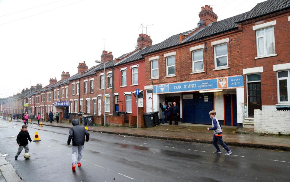 Children play football outstand an entrance to Luton's Kenilworth Road stadium - alamy