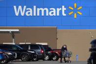 FILE - A woman wheels a cart with her purchases out of a Walmart store, Nov. 18, 2020, in Derry, N.H. Business closings on Christmas Eve are less common than those on Christmas Day, but many large chains still cut back hours or close up shop early for the coming holiday. Walmart will close at 6 p.m. on Christmas Eve, Sunday, Dec. 24, 2023. (AP Photo/Charles Krupa, File)