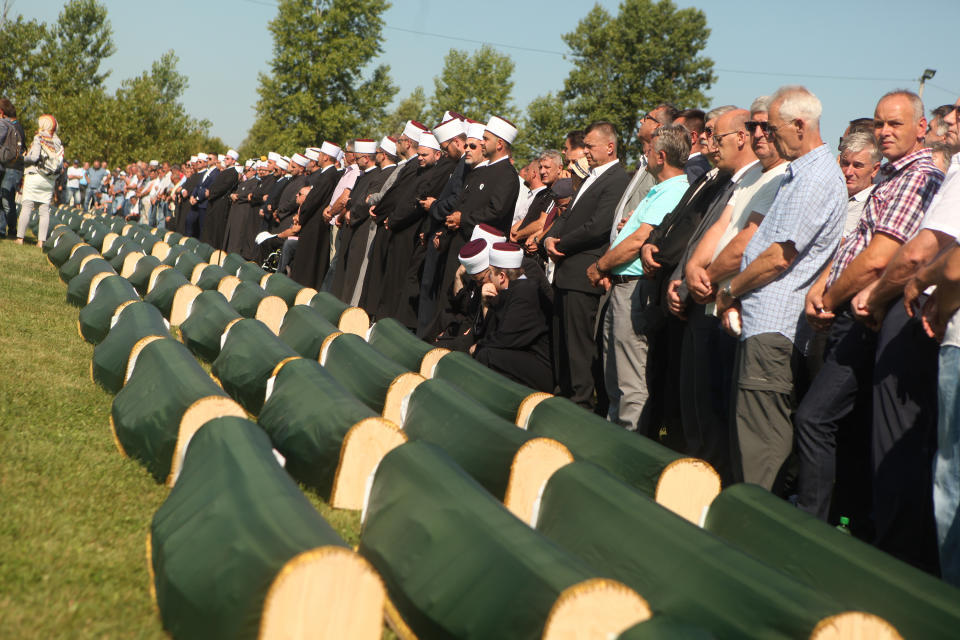 Relatives and friends of the victims, with religious leaders among the some thousands of mourners gathered at a soccer stadium in Kozarac near the town of Prijedor, behind the coffins draped with green cloth for the funeral of 86 Muslims, Saturday July 20, 2019. The victims were slain by Serbs in one of the worst atrocities of the country's 1992-95 war, aged 19 to 61, and were among some 200 Bosnian Muslims and Croats from Prijedor who were executed in Aug. 1992 on a cliff on Mt. Vlasic known as Koricanske Stijene. (AP Photo/Almir Alic)