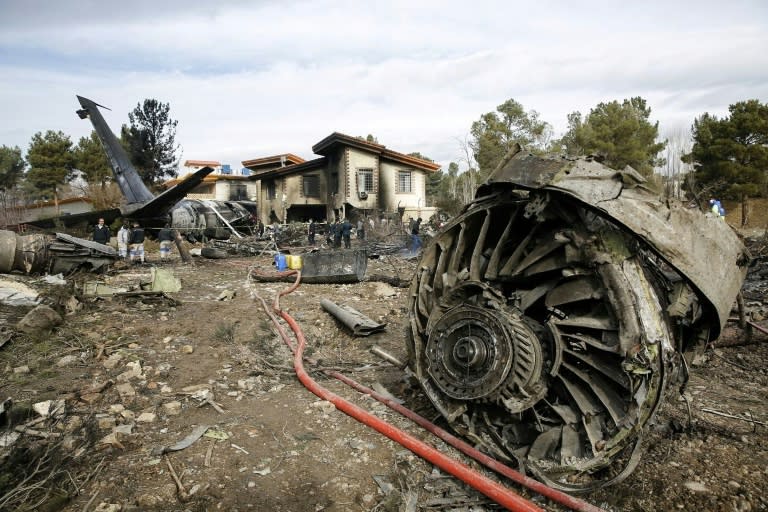 Firefighters and security forces gather at the crash site of a Boeing 707 cargo plane that slammed into a residential complex near the Iranian capital Tehran with at least 10 people onboard on January 14, 2019