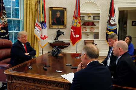 U.S. President Donald Trump answers question from Reuters reporters Steve Holland, Jeff Mason and James Oliphant as White House Press Secretary Sarah Huckabee Sanders listens during an interview with Reuters in the Oval Office of the White House in Washington, U.S. August 20, 2018. REUTERS/Leah Millis