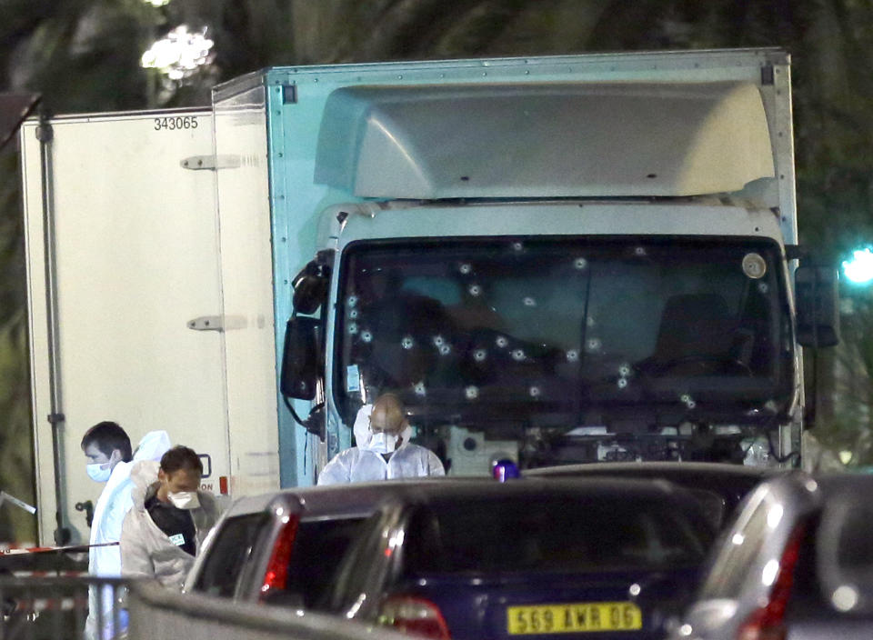 Forensic officers stands near a truck with its windscreen riddled with bullets, that plowed through a crowd of revelers who'd gathered to watch the fireworks in the French resort city of Nice, southern France, Friday, July 15, 2016. Eight people go on trial Monday Sept.5, 2022 in a special French terrorism court for alleged roles in helping the attacker who drove a truck into the Nice beachfront on Bastille Day 2016, killing 86 people. (AP Photo/Claude Paris, File)