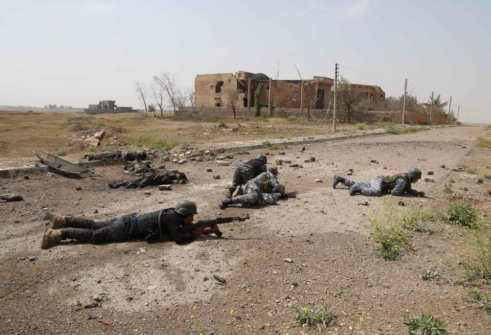 In this Monday, March 30, 2015 file photo, Iraqi security forces attack Islamic State extremists as they take up positions next to the bodies of Islamic State fighters in Tikrit, 80 miles  north of Baghdad, Iraq. (AP Photo/Khalid Mohammed, File)