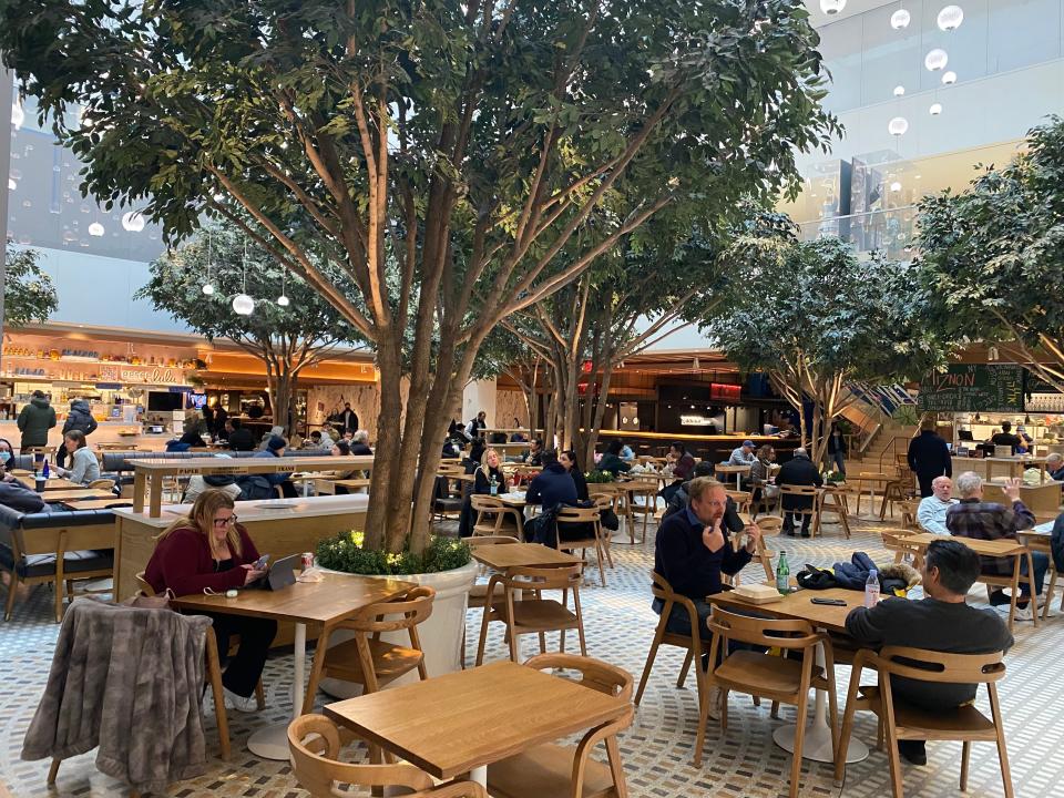 Outdoors restaurant seating around planted trees.