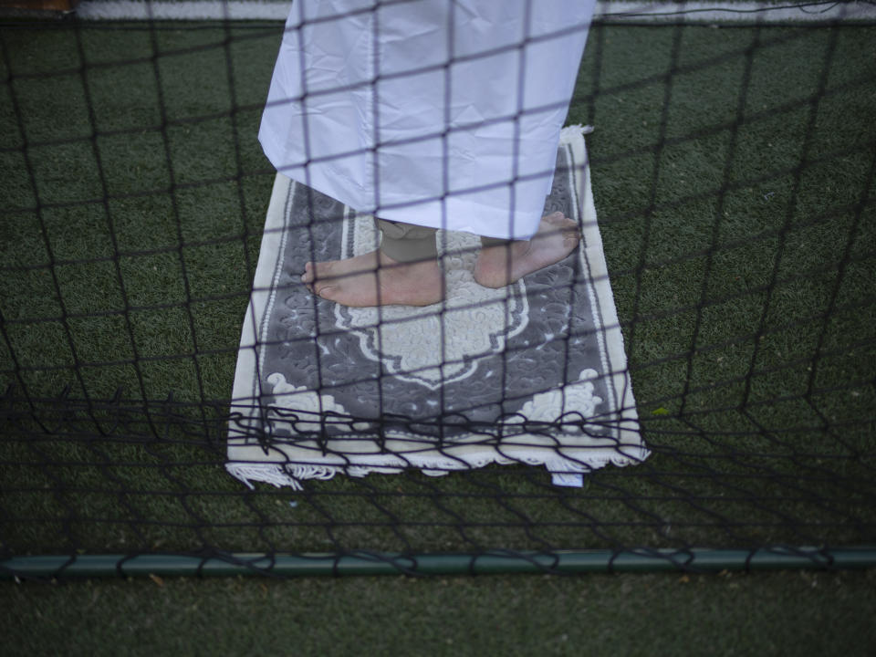 A Muslim worshipper offers Eid al-Fitr prayers marking the end of the holy fasting month of Ramadan at the Malpasse soccer stadium in Marseille, southern France, Wednesday, April 10, 2024. (AP Photo/Daniel Cole)