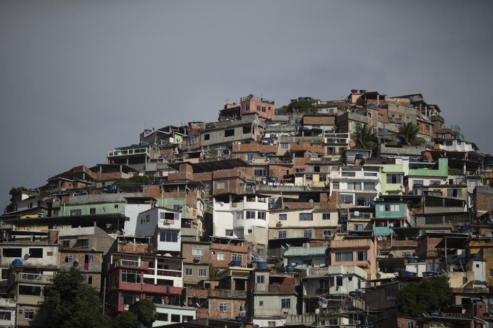 In this May 31, 2019 photo, cinderblock homes blanket a hill in the Vidigal slum in Rio de Janeiro, Brazil. According to the non-government violence monitor Crossfire, a growing number of people in Rio are hit, often killed, each year by stray bullets, some fired by criminals, some by police. (AP Photo/Leo Correa)