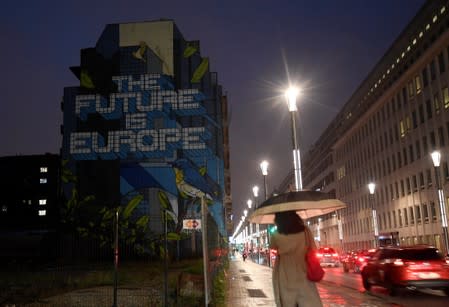 Woman walks along a street in the early morning near a lettering reading "The Future is Europe" near the European Council headquarters ahead of an EU summit in Brussels