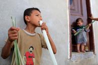 Sayed Abdul Rahman, 9, cuts papyrus plant with his mouth at a workshop in al-Qaramous village
