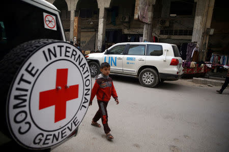 A Syrian child is seen walking near International Red Cross vehicle in the rebel-held city of Douma, in the eastern Damascus suburb of Ghouta, Syria November 12, 2017. REUTERS/Bassam Khabieh