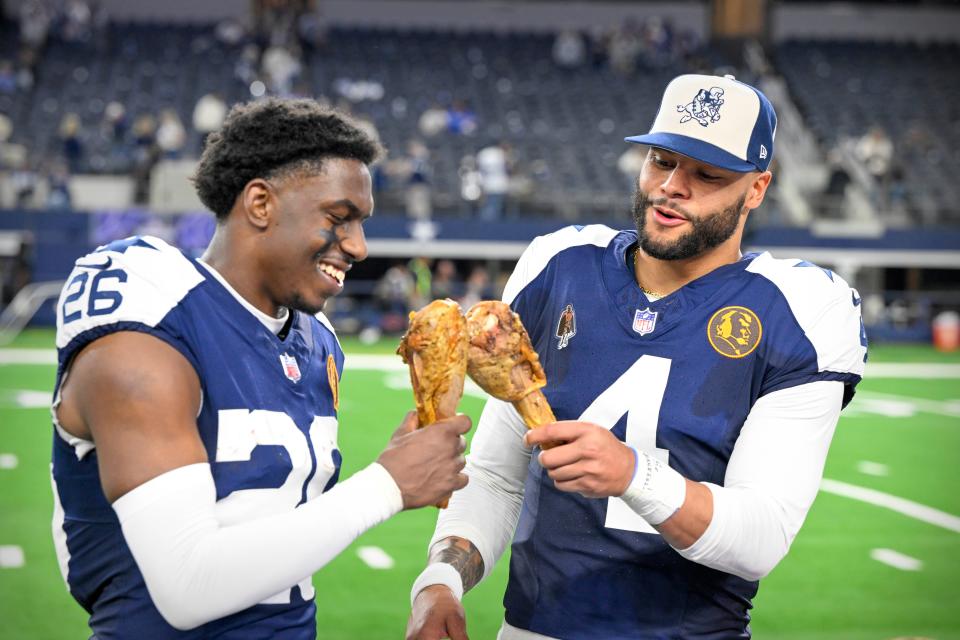 Dallas Cowboys cornerback DaRon Bland (26) and quarterback Dak Prescott eat turkey legs after the Cowboys' victory over the Washington Commanders.