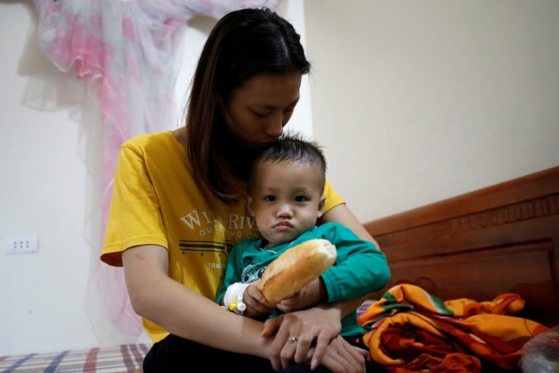 Hoang Thi Thuong, wife of Nguyen Dinh Tu, a Vietnamese suspected victim in a truck container in UK, holds her son Nguyen Dinh Dan at their home in Nghe An province