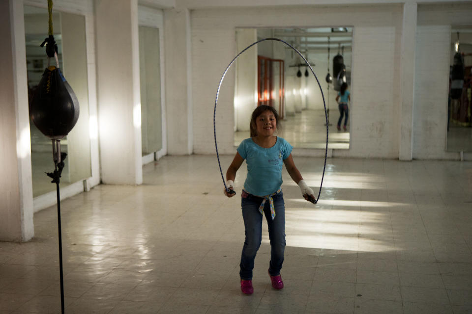 In this April 11, 2014 photo, a girl jumps rope in a boxing gym as visitors arrive on a theatrical tour of Mexico City's Tepito neighborhood. Tepito's tough reputation is well-earned. Along with the killings in recent years, residents sometimes fight with rocks and glass bottles against police trying to conduct raids at houses believed to be sheltering drugs and pirated merchandise. The neighborhood has also earned its fierce reputation through its history of producing professional boxers. (AP Photo/Rebecca Blackwell)