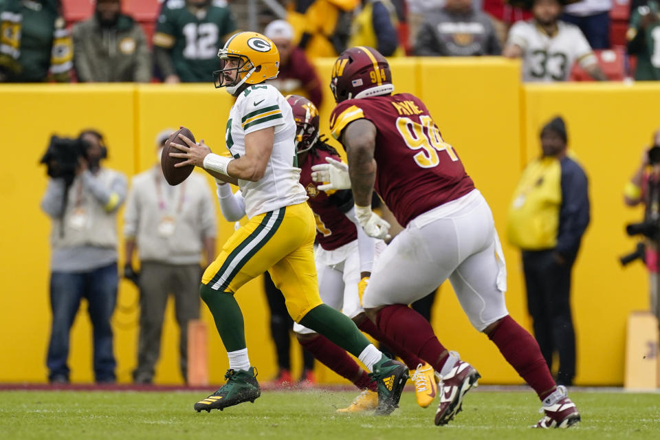 Green Bay Packers quarterback Aaron Rodgers (12) runs with the ball as he is chased by Washington Commanders defensive tackle Daron Payne (94) on the last play of an NFL football game Sunday, Oct. 23, 2022, in Landover, Md. (AP Photo/Patrick Semansky)