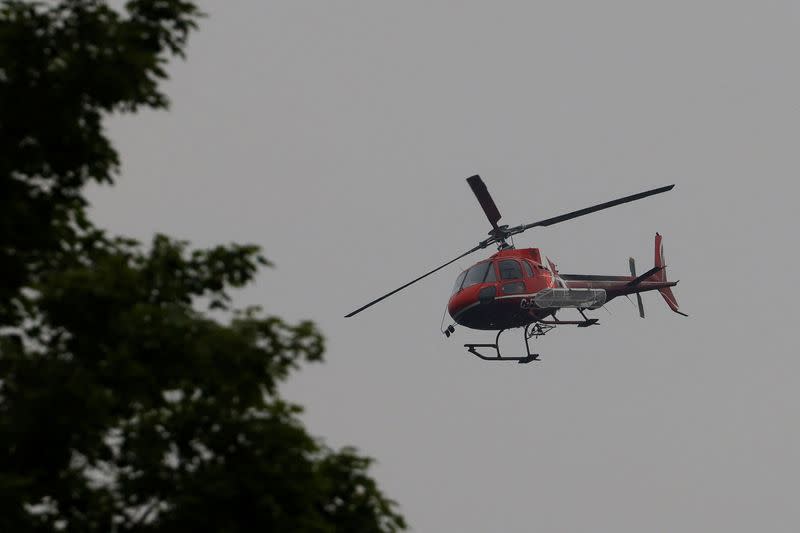 A helicopter prepares to land in a staging area near a forest fire that has been burning since Sunday on the shore of Centennial Lake in the Township of Greater Madawaska