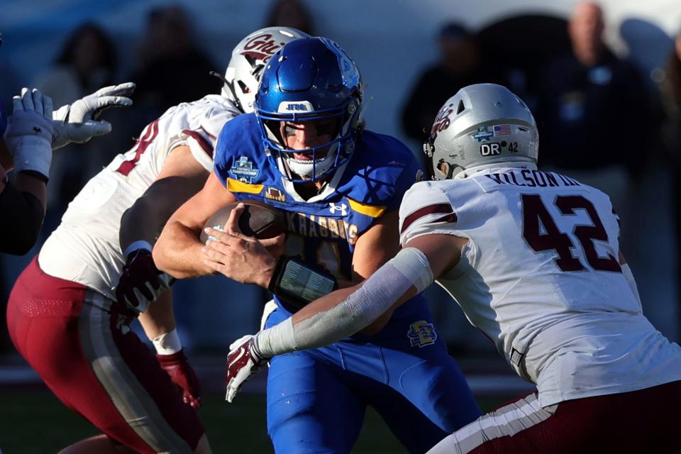 South Dakota State quarterback Mark Gronowski, center, runs the ball as Montana linebacker Riley Wilson (42) looks to tackle him in the second half at the FCS Championship NCAA college football game Sunday, Jan. 7, 2024, in Frisco, Texas. (AP Photo/Richard W. Rodriguez)