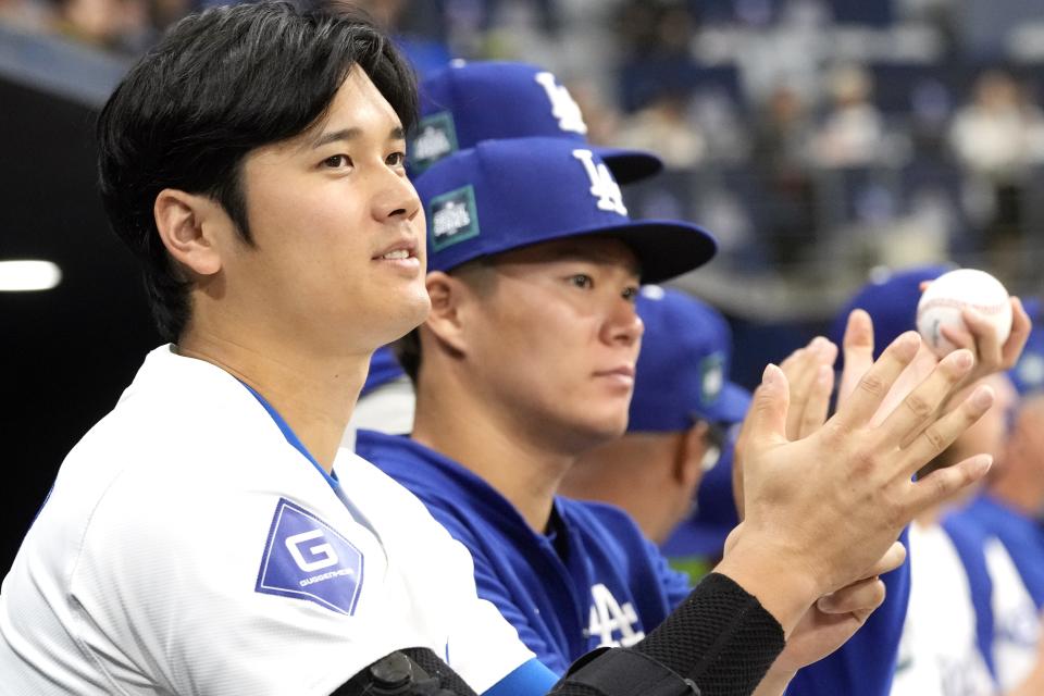 Los Angeles Dodgers' designated hitter Shohei Ohtani , left, and pitcher Yoshinobu Yamamoto , right, applaud in the first inning of the exhibition game between the Los Angeles Dodgers and Kiwoom Heroes at the Gocheok Sky Dome in Seoul, South Korea, Sunday, March 17, 2024. The Los Angeles Dodgers and the San Diego Padres will meet in a two-game series on March 20th-21st in Seoul for the MLB World Tour Seoul Series. (AP Photo/Ahn Young-Joon)