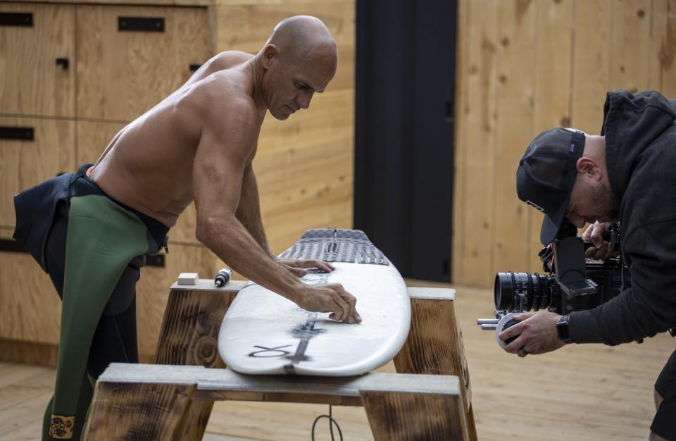 Kelly Slater waxes his board on the set of "The Ultimate Surfer."