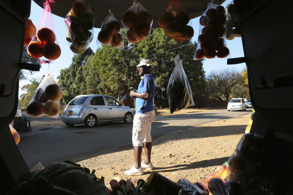 A man displays fruits and vegetables inside his car trunk while selling them by the side of a busy road in Harare, Zimbabwe, Tuesday, July 7, 2020. Cars have become mobile markets in Zimbabwe where enterprising residents are selling goods from their vehicles to cope with economic hardships caused by the coronavirus. With their car doors and trunks wide open by the side of busy roads, eager sellers display a colorful array of goods in Harare, the capital. (AP Photo/Tsvangirayi Mukwazhi)