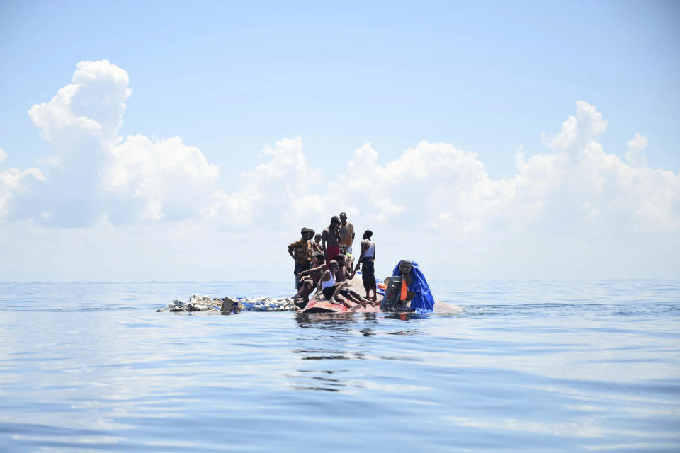 Rohingya refugees stand on their capsized boat before being rescued in the waters off West Aceh, Indonesia, Thursday, March 21, 2024. The wooden boat carrying dozens of Rohingya Muslims capsized off Indonesia's northernmost coast on Wednesday, according to local fishermen. (AP Photo/Reza Saifullah)