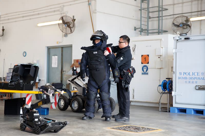 A colleague assists an EOD officer in putting on a protective suit during a media tour of the EOD depot of the Hong Kong police in Hong Kong