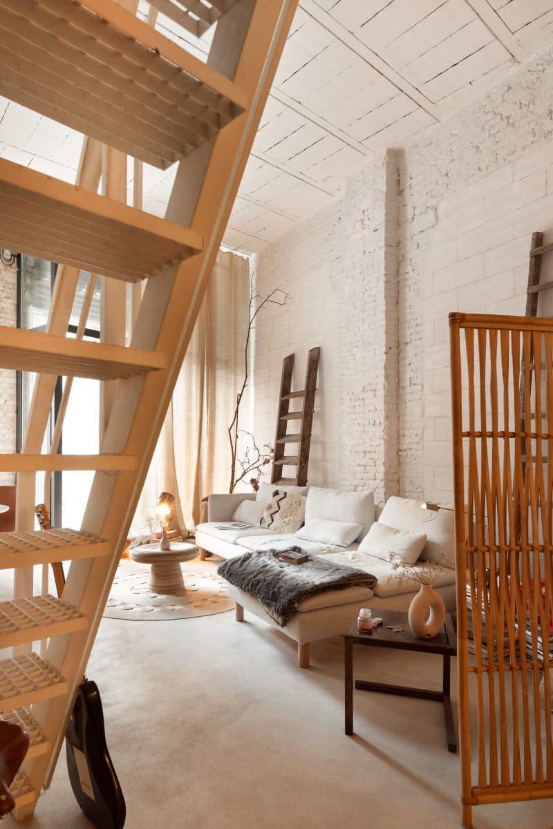 White brick living room with off white sofa, stone floor, large windows, and lots of neutral and warm tones