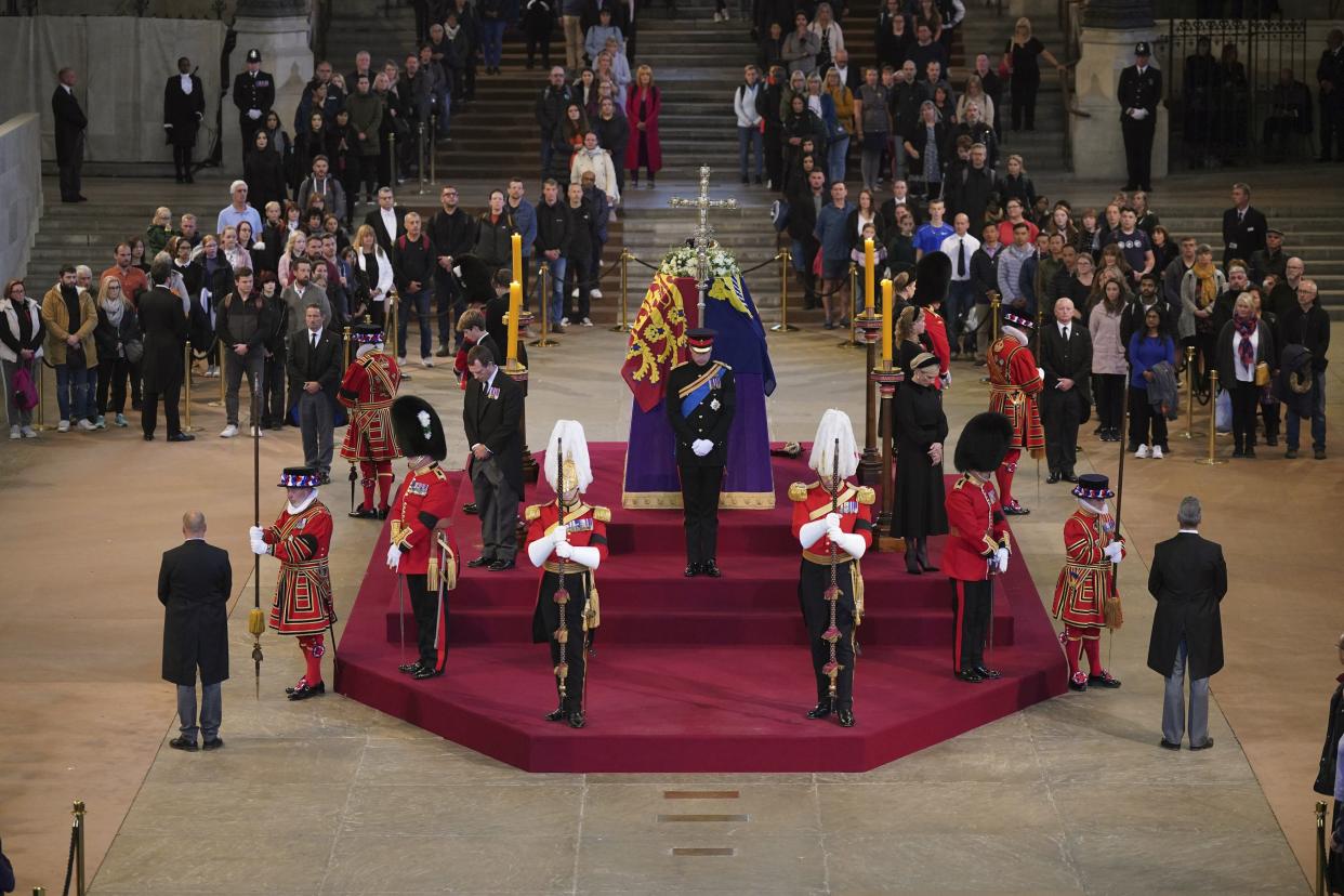 FILE - Queen Elizabeth II 's grandchildren, clockwise from foreground centre, Prince William, the Prince of Wales, Peter Phillips, James, Viscount Severn, Princess Eugenie, Prince Harry, the Duke of Sussex, not seen, Princess Beatrice, Lady Louise Windsor and Zara Tindall take part in a vigil of the Queen's grandchildren, as they stand by the coffin of Queen Elizabeth II, as it lies in state, in Westminster Hall, at the Palace of Westminster, London, Saturday, Sept. 17, 2022, ahead of her funeral on Monday. When Queen Elizabeth II’s grandfather, King George V, died in 1936, life in Britain is unrecognizable to people today. But despite almost a century of change, the images from the queen’s lying in state this week are almost exact copies of those from George V’s time.  (Yui Mok/Pool Photo via AP, File)