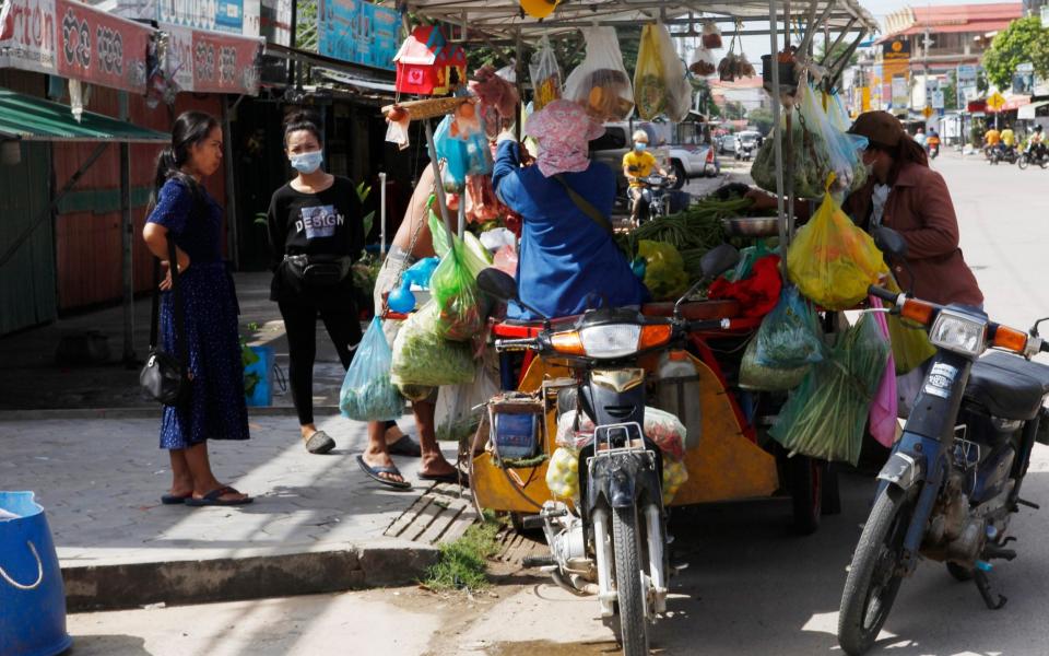 Customers buy some foods from a motor-cart's mobile market during lockdown, - Heng Sinith/AP