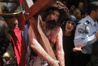 A man playing the role of Jesus carries a cross during a procession along the Via Dolorosa on Good Friday during Holy Week, in Jerusalem's Old City April 18, 2014. Christian worshippers on Friday retraced the route Jesus took along Via Dolorosa to his crucifixion in the Church of the Holy Sepulchre. Holy Week is celebrated in many Christian traditions during the week before Easter.