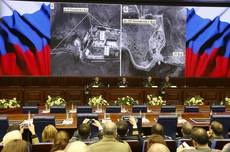 Defence ministry officials sit under screens with satellite images on display during a briefing in Moscow, Russia, December 2, 2015. REUTERS/Sergei Karpukhin